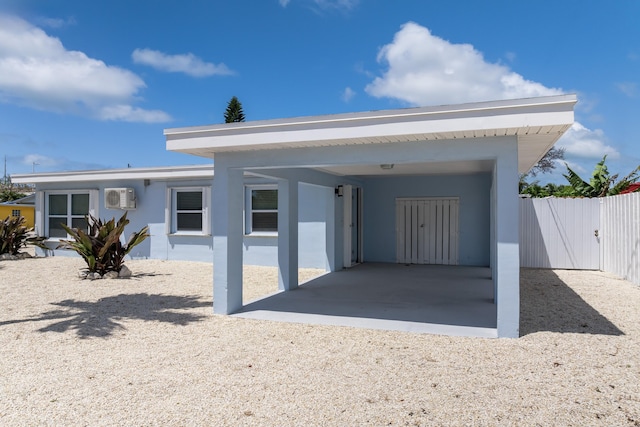 ranch-style home with an AC wall unit, stucco siding, a gate, and fence