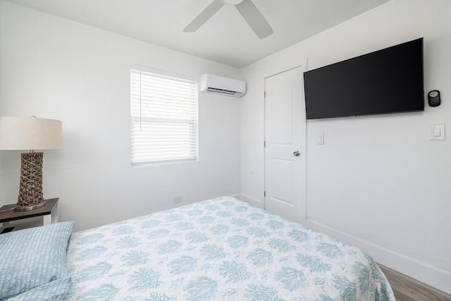 bedroom with a ceiling fan, baseboards, wood finished floors, and a wall mounted air conditioner