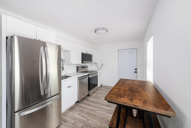 kitchen featuring light wood-type flooring, light countertops, appliances with stainless steel finishes, and white cabinets