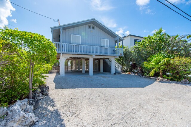 681 Indies Dr, Ramrod, FL 33042 - raised beach house featuring a carport, gravel driveway, board and batten siding, and stairs
