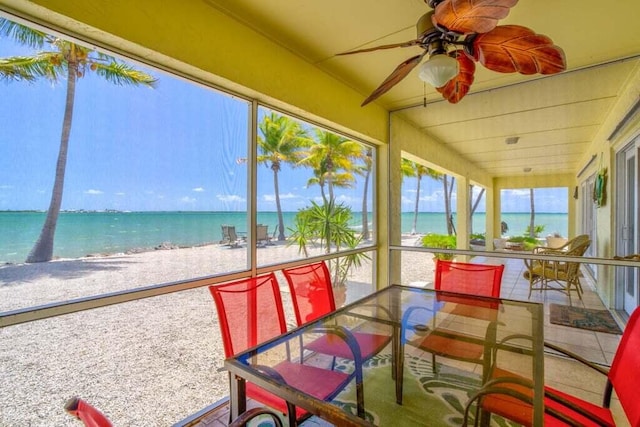 sunroom featuring plenty of natural light, a beach view, and a water view