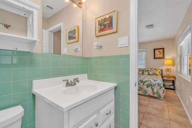 bathroom with toilet, tile walls, visible vents, and vanity