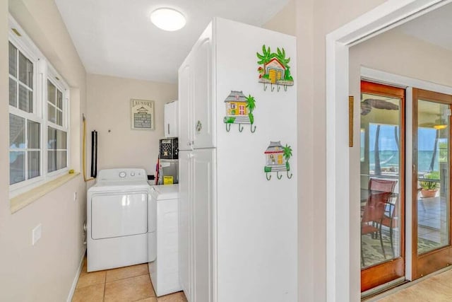 clothes washing area featuring cabinet space, baseboards, light tile patterned floors, and washer and dryer