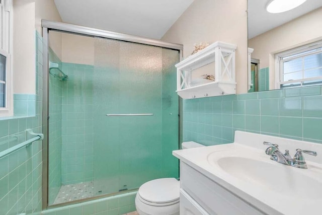 bathroom with toilet, tile walls, a shower stall, and vanity