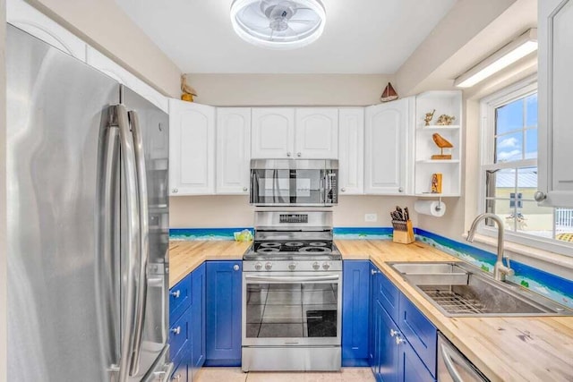 kitchen with blue cabinets, a sink, white cabinetry, and stainless steel appliances
