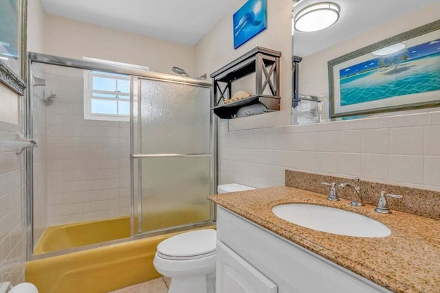 bathroom featuring shower / bath combination with glass door, vanity, toilet, tile walls, and decorative backsplash
