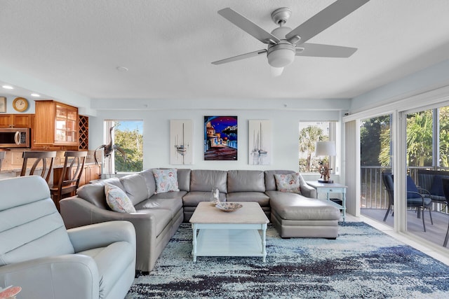 living room featuring a textured ceiling, ceiling fan, and a wealth of natural light