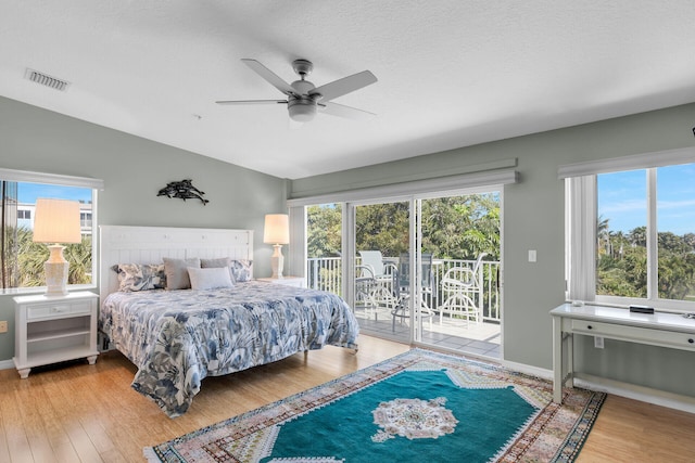 bedroom with access to exterior, lofted ceiling, visible vents, and wood finished floors