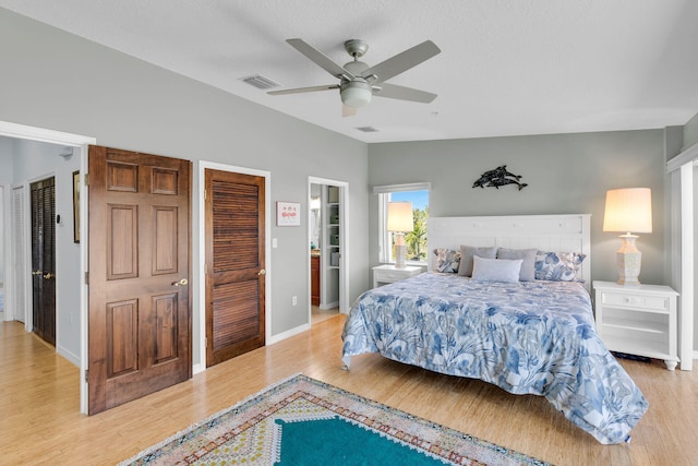 bedroom with lofted ceiling, visible vents, light wood-style flooring, a ceiling fan, and baseboards