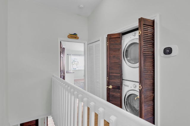 laundry area with laundry area, baseboards, and stacked washer and clothes dryer