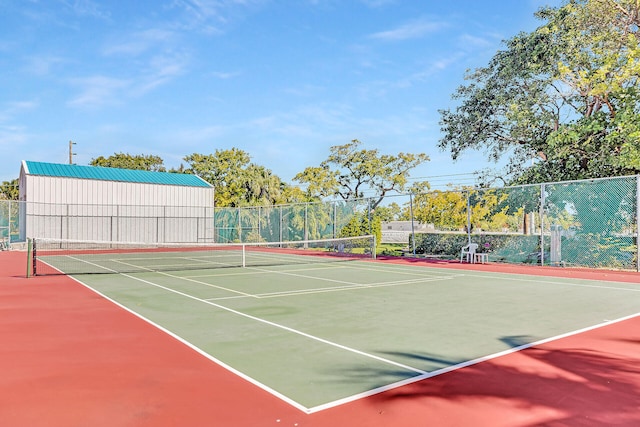 view of tennis court featuring community basketball court and fence