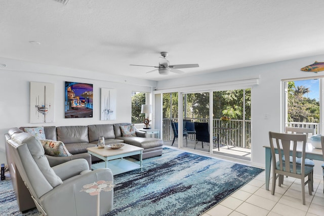 living area featuring ceiling fan, a textured ceiling, and light tile patterned floors