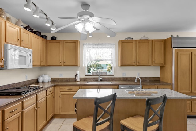 kitchen featuring white microwave, a breakfast bar area, and a kitchen island with sink