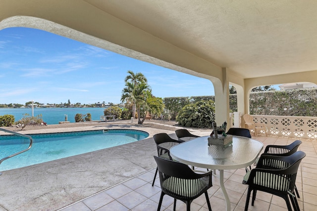 outdoor pool featuring a patio area and a water view