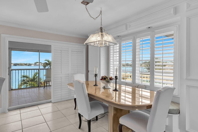 dining space with light tile patterned floors, ornamental molding, a water view, and a notable chandelier