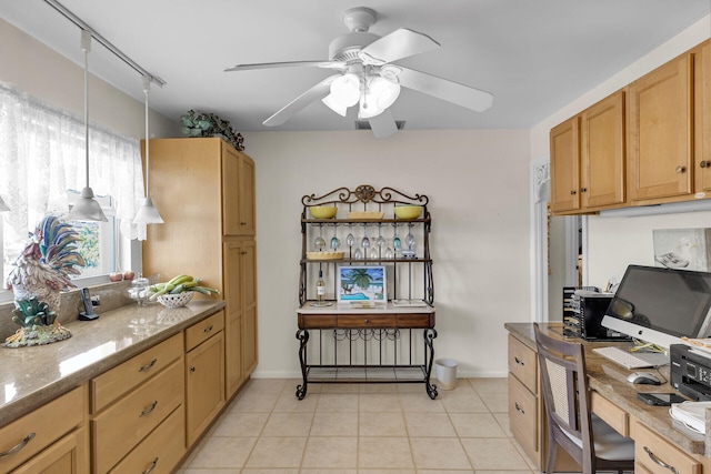 kitchen with light stone counters, hanging light fixtures, light tile patterned flooring, ceiling fan, and baseboards