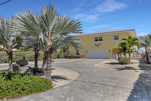 view of front of property with a garage, decorative driveway, fence, and stucco siding