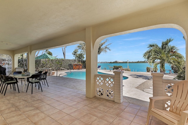 view of patio featuring a water view, fence, an outdoor pool, and outdoor dining space