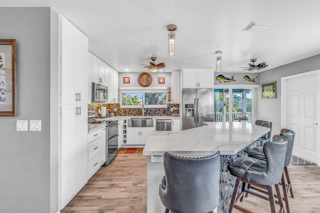 421 Ixora Dr, Big Pine, FL 33043 - kitchen with stainless steel appliances, ceiling fan, a breakfast bar, a center island, and white cabinetry