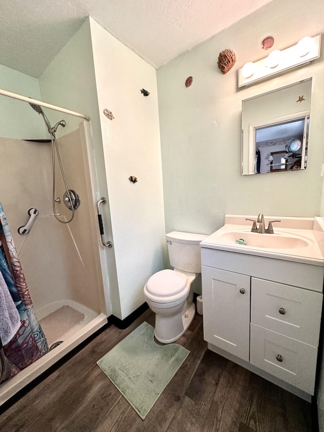 bathroom featuring a textured ceiling, a shower stall, toilet, and wood finished floors