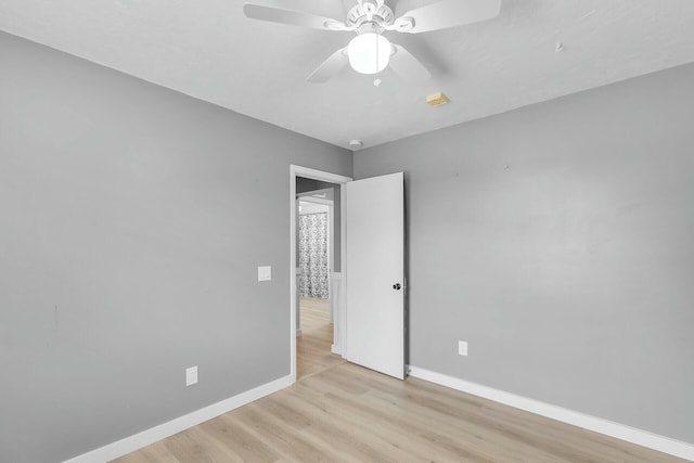 empty room with a ceiling fan, light wood-style floors, and baseboards