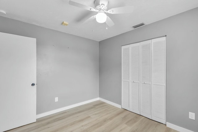 unfurnished bedroom featuring visible vents, baseboards, wood finished floors, a closet, and a ceiling fan