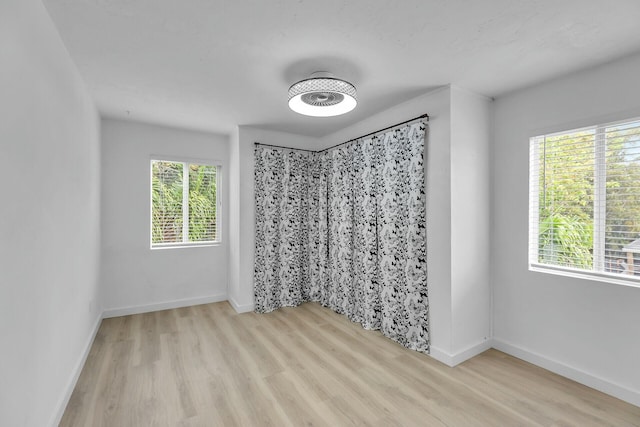 empty room with a wealth of natural light, baseboards, and wood finished floors