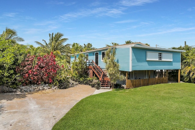 rear view of house featuring a carport, a lawn, and stairs