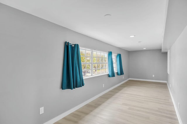 empty room featuring recessed lighting, baseboards, and light wood-type flooring