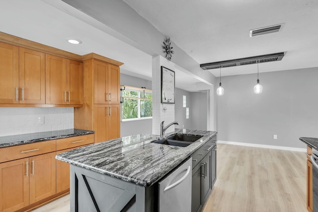 kitchen featuring tasteful backsplash, visible vents, dark stone counters, stainless steel dishwasher, and a sink