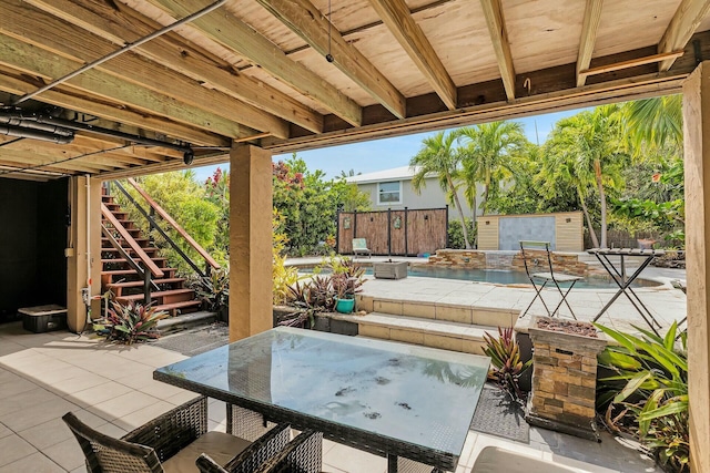 view of patio / terrace featuring fence, outdoor dining area, stairs, a swimming pool, and a jacuzzi