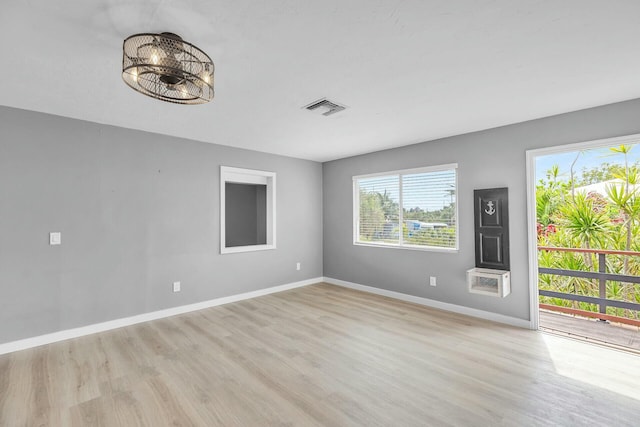 spare room with light wood-type flooring, visible vents, and baseboards