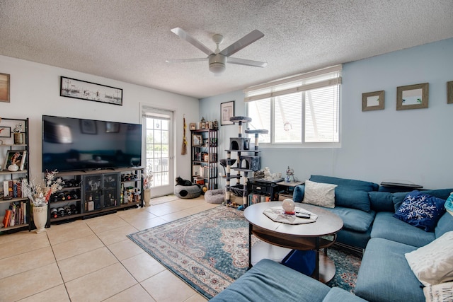 living room with ceiling fan, a textured ceiling, and light tile patterned flooring