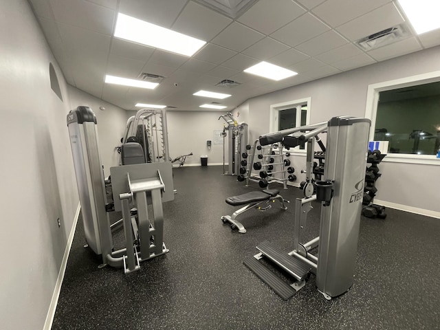 workout area with baseboards, visible vents, and a drop ceiling