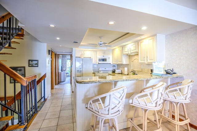 1133 Ocean Dr Unit 2, Key Colony, FL 33051 - kitchen featuring white appliances, light stone countertops, a peninsula, recessed lighting, and a ceiling fan