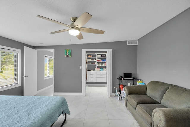 bedroom featuring a spacious closet, marble finish floor, visible vents, baseboards, and ceiling fan