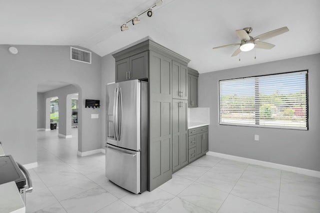 kitchen featuring visible vents, arched walkways, gray cabinetry, stainless steel fridge, and ceiling fan