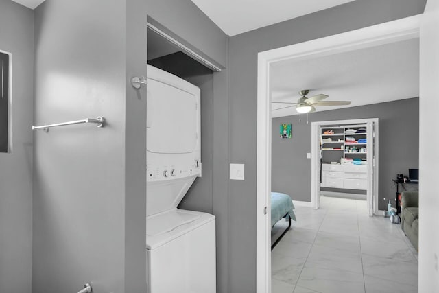 laundry area with marble finish floor, stacked washing maching and dryer, laundry area, and ceiling fan