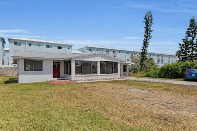 rear view of house with stucco siding, a standing seam roof, metal roof, and a lawn