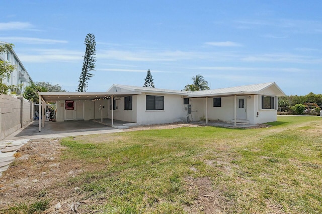 back of house with an attached carport, metal roof, fence, a yard, and stucco siding