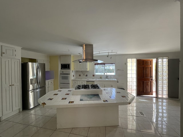 27858 Lobster Tail Trl, Little Torch, FL 33042 - kitchen featuring stainless steel refrigerator with ice dispenser, oven, tile countertops, built in microwave, and island exhaust hood