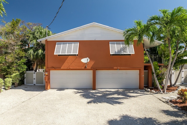 view of front facade featuring a garage, a gate, driveway, and stucco siding