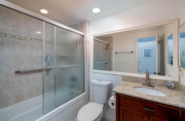 bathroom featuring toilet, recessed lighting, enclosed tub / shower combo, and vanity