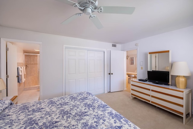 bedroom featuring a closet, light colored carpet, visible vents, ensuite bathroom, and ceiling fan