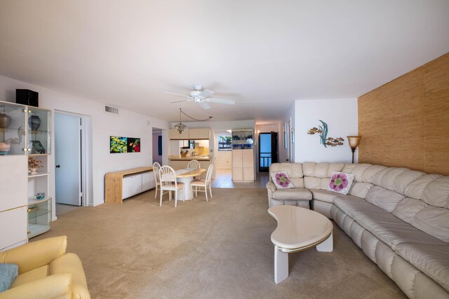 living area featuring carpet floors, visible vents, and ceiling fan