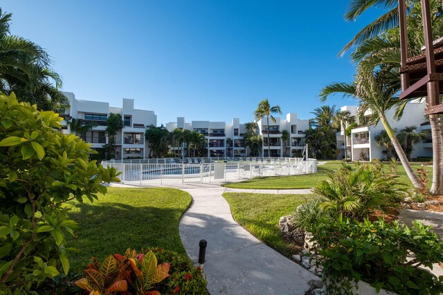 view of property's community with a swimming pool, fence, a lawn, and a residential view