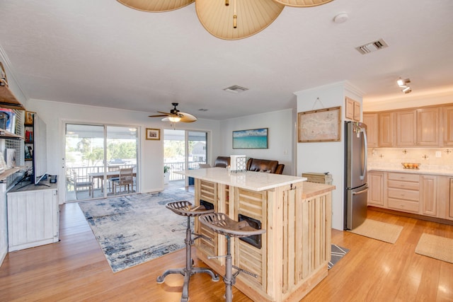 kitchen with visible vents, open floor plan, light countertops, freestanding refrigerator, and light brown cabinetry