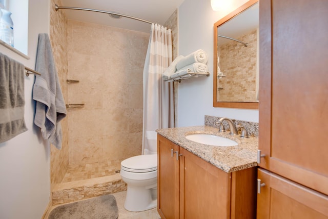 bathroom featuring a tile shower, vanity, and toilet