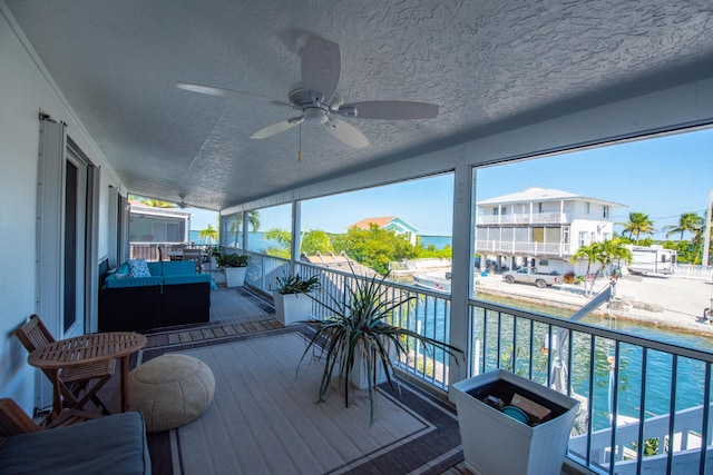 wooden terrace with a ceiling fan and a water view