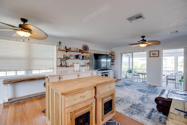 kitchen featuring wooden counters, a center island, visible vents, and light wood-style floors